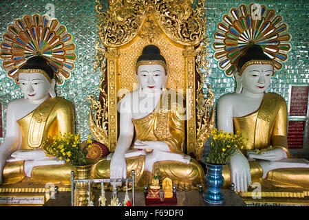 SAGAING, Myanmar — debout sur une colline à Sagaing, la pagode OoHminThoneSel présente une longue alcôve incurvée bordée de dizaines de statues du Bouddha. Après de récentes rénovations et améliorations en cours rendues possibles par des donateurs, la pagode est richement décorée avec des mosaïques de carreaux colorés et de la peinture fraîche et brillante. Banque D'Images