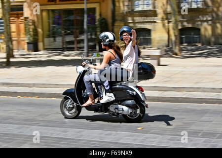 Aix-en-Provence Sud de la France les jeunes carefree woman waving & équitation leurs scooters sur le long Cours Mirabeau boulevard en juillet chaud jour d'été Banque D'Images