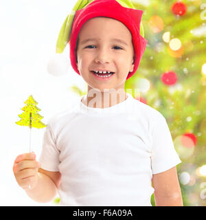 Portrait de Noël d'un enfant habillé comme un elfe avec des bonbons dans la forme d'un arbre de Noël Banque D'Images