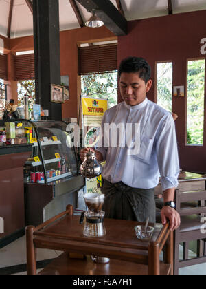 Serveur dans un café à Pyin Oo Lwin (Maymyo) au Myanmar la préparation du café fraîchement moulu, verser de l'eau chaude sur le café moulu. Banque D'Images