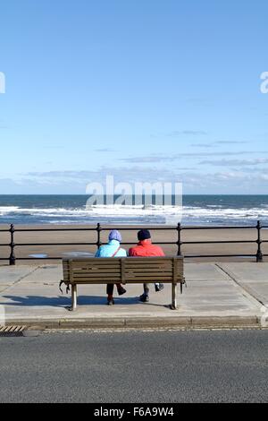 Couple de personnes âgées assis sur banc front à Scarborough dans le Yorkshire Banque D'Images