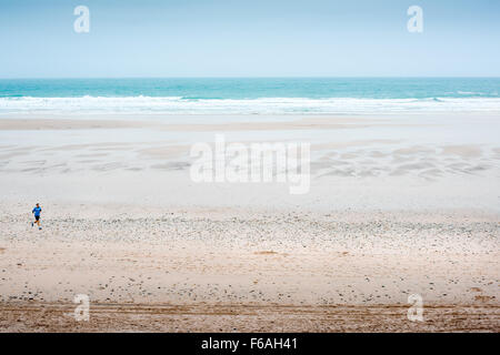 Jogger sur la plage de sable de la plage de Fistral à Newquay, Angleterre. Banque D'Images