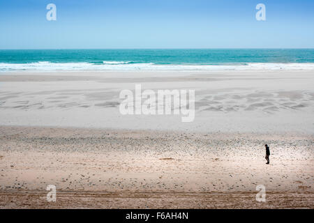 Homme marche le long de la plage de Fistral à Newquay, Angleterre. Banque D'Images