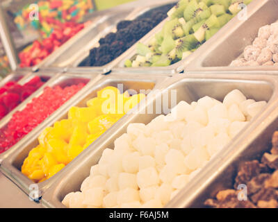 Le yogourt glacé garniture bar. Garnitures yogourt allant des fruits frais, des noix, des bonbons, des sirops et des paillettes. Banque D'Images