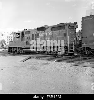 Cette image présente la nouvelle Louis Southwestern Diesel Electric Road Switcher No. 827, un type de locomotive utilisé pour changer de wagons. La peinture met en valeur les gares de triage, les bâtiments clés comme le Texas School Book Depository et l'historique Cotton Belt route. Banque D'Images