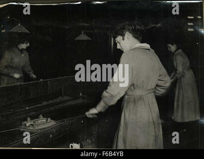 Cette image représente le processus de redressement des bandes de lames pendant la première Guerre mondiale. Elle fait partie des efforts déployés en temps de guerre pour préparer des matériaux pour la fabrication d'armes, montrant les aspects industriels du conflit. Banque D'Images