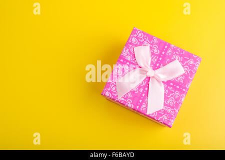 Boîte cadeau rose sur fond jaune, vue du dessus Banque D'Images