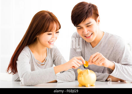 Happy young Couple Insertion Coin In Piggybank Banque D'Images