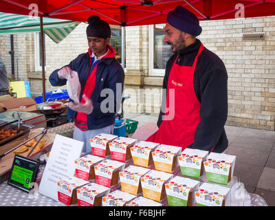 Deux hommes sikhs porteurs de décrochage à un marché de producteurs britanniques servant Sauces au cari et cuit 'vraiment' marque Indian food Banque D'Images