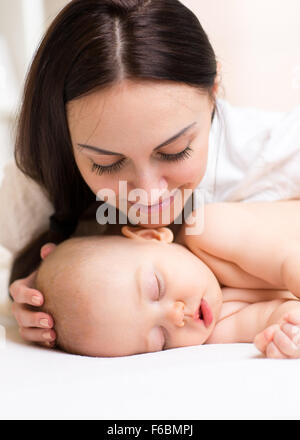 Heureux mère regardant bébé endormi Banque D'Images