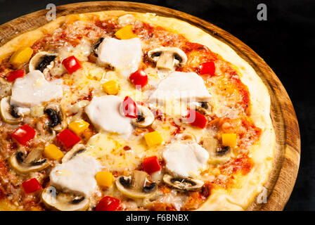 La pizza sur un fond sombre avec du jambon, champignons, fromage et piment doux Banque D'Images
