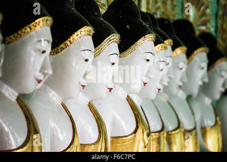 SAGAING, Myanmar — debout sur une colline à Sagaing, la pagode OoHminThoneSel présente une longue alcôve incurvée bordée de dizaines de statues du Bouddha. Après de récentes rénovations et améliorations en cours rendues possibles par des donateurs, la pagode est richement décorée avec des mosaïques de carreaux colorés et de la peinture fraîche et brillante. Banque D'Images