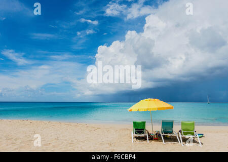 Trois chaises de plage sous un parapluie jaune donnent sur une tempête tropicale sur les Caraïbes. St, croix, Îles Vierges des États-Unis. Banque D'Images