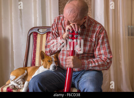 Jeune chien et musicien mature ayant peu de repos après les performances Banque D'Images