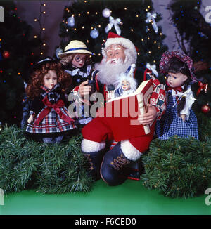 Les fêtes de Nouvel An, Noël encore la vie avec des jouets-santa lit le livre à trois poupées sous un Nouvel An des arbres. format carré. Banque D'Images