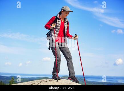 Jeune femme marche touristique en montagne avec des bâtons. Sur fond de ciel bleu. Banque D'Images