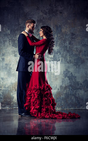 Jeune couple aimant élégante robe de soirée en portrait. Femme en rouge et l'homme en costume noir. Banque D'Images