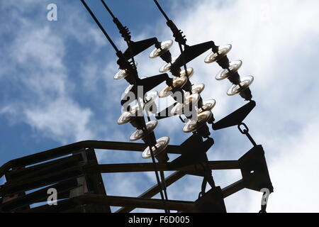 Les connecteurs de câble à haute tension et isolateurs de verre contre le ciel bleu avec des nuages Banque D'Images