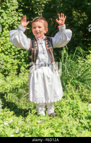 Paysan Roumain Enfant vêtu d'un costume traditionnel danse une danse traditionnelle roumaine dans l'arrière-cour de sa maison Banque D'Images