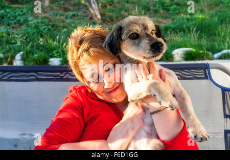 Hunedoara, Roumanie - 01 juillet 2014 : Happy Blonde Woman embrayer sur la poitrine en Hunedoara chien nouvellement adoptée le 1 juillet 2014 Banque D'Images