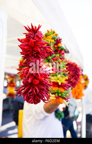 Poivrons colorés suspendus et pendaison en marché. Banque D'Images