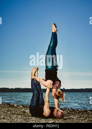 Couple sportif yoga acro de formation à l'extérieur, l'été, mer, ciel bleu Banque D'Images