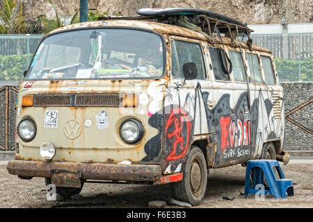 LIMA, PÉROU - 12 octobre 2014 : Volkswagen van épave rouillée utilisé comme stockage d'équipement de surf, vu à Lima, Pérou Plage. Banque D'Images