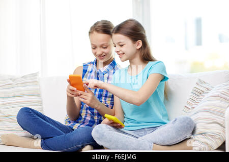 Heureux les filles avec les smartphones sitting on sofa Banque D'Images