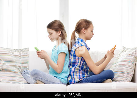 Les filles avec les smartphones sitting on sofa at home Banque D'Images