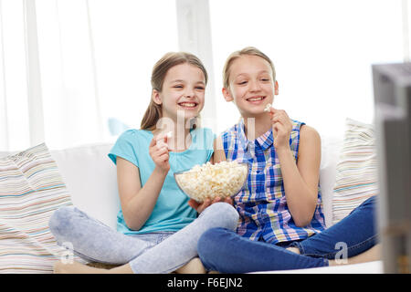 Les filles heureuse avec le pop-corn en regardant la télé à la maison Banque D'Images