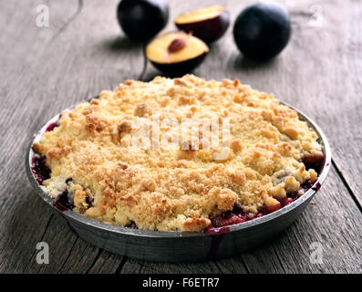 Tarte aux prunes crumb dans le moule, sur fond de bois Banque D'Images