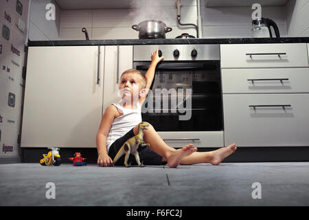 La prévention des accidents. L'enfant sans surveillance dans la cuisine avec une cuisinière à gaz. Banque D'Images