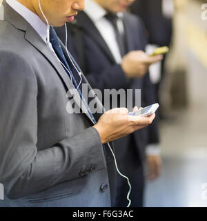 Hommes d'utiliser leurs téléphones cellulaires sur metro. Banque D'Images