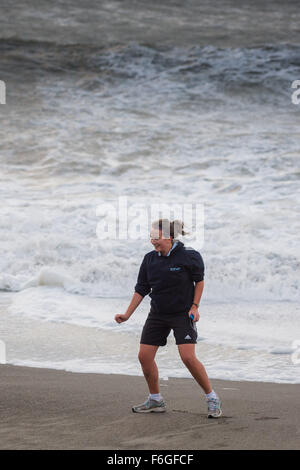 Pays de Galles Aberystwyth Uk, le mardi 17 novembre 2015 UK weather : Une jeune femme pose sur la plage comme derrière elle les vagues de la deuxième ouragan de la saison - Storm Barney - hits Aberystwyth, sur la côte ouest du pays de Galles. Rafales de vent devaient atteindre 80km/h sur les hauteurs, et les fortes pluies susceptibles de causer des inondations dans les zones déjà saturées après des jours de pluie Crédit photo : Keith Morris / Alamy Live News Banque D'Images