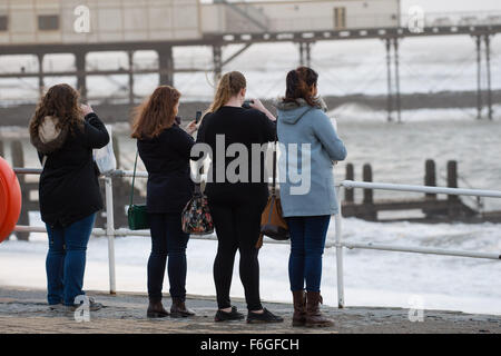 Pays de Galles Aberystwyth Uk, le mardi 17 novembre 2015 UK weather : un groupe de jeunes femmes photographie les vagues comme le deuxième ouragan de la saison - Storm Barney - hits Aberystwyth, sur la côte ouest du pays de Galles. Rafales de vent devaient atteindre 80km/h sur les hauteurs, et les fortes pluies susceptibles de causer des inondations dans les zones déjà saturées après des jours de pluie Crédit photo : Keith Morris / Alamy Live News Banque D'Images