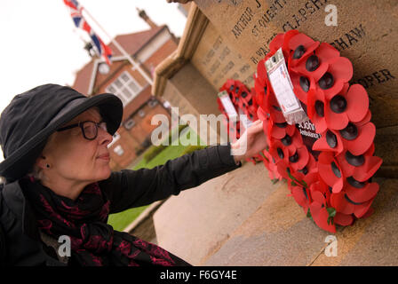 Woman inspecting une couronne portée par St John Ambulance au monument aux morts au cours de la commémoration du Jour du Souvenir 2015 service... Banque D'Images