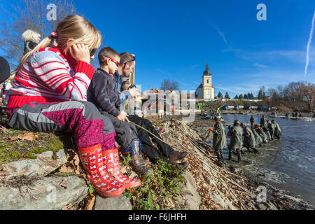 Les enfants sur la digue regarder les récoltes traditionnelles de l'étang des carpes tchèque. Bosilec La Bohême du Sud, République Tchèque Banque D'Images