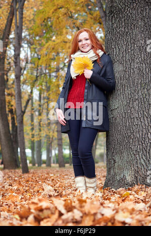 Redhead girl with leaf dans city park, saison d'automne Banque D'Images