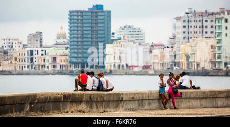 Les adolescents cubains à poser des briques du Malecon, La Havane à l'arrière-plan, scène de rue, La Habana, Cuba, Caraïbes, Amérique du Nord Banque D'Images