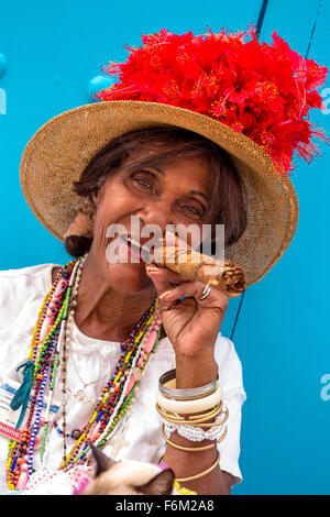 Vieille Femme cubaine fume dans la rue un cigare cubain et poster avec son chat pour les touristes, de Cuba, de l'Amérique du Nord, Caraïbes Banque D'Images