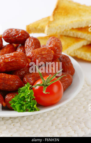 Assiette de mini-saucisses et toasts croustillants sur tableau blanc mat Banque D'Images