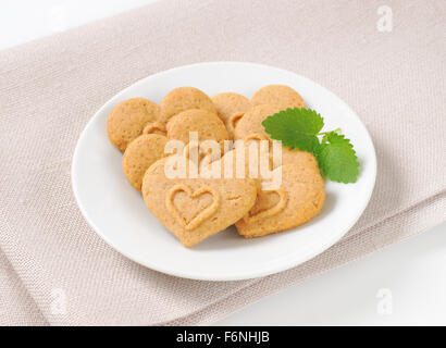 Close up de cookies en forme de cœur et de menthe sur plaque blanche et beige mat place Banque D'Images