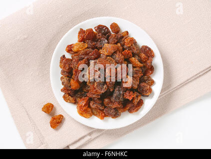 Assiette de raisins secs sur napperon beige Banque D'Images