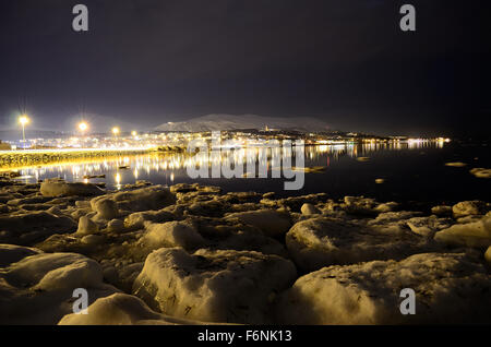 Mer de neige avec des lumières de la ville et le fjord en hiver surface réfléchissantes la nuit Banque D'Images