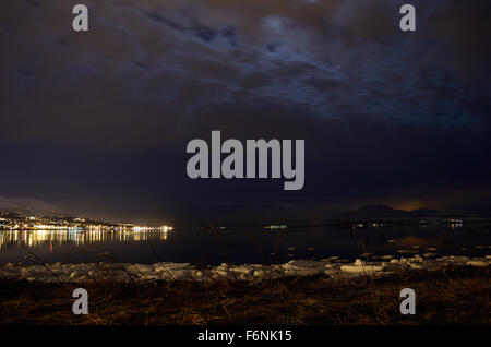 Mer de neige avec des lumières de la ville et le fjord en hiver surface réfléchissantes la nuit Banque D'Images