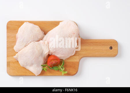 Pilons de poulet crus sur planche à découper en bois Banque D'Images