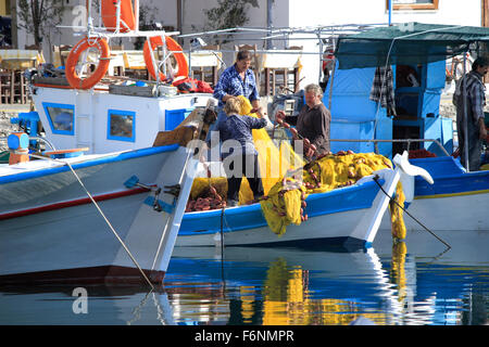 Les pêcheurs dans leurs bateaux, réparation des filets de pêche de couleur jaune. Myrina Lemnos, quai ou l'île de Limnos, Grèce. Banque D'Images