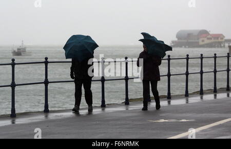 Swansea, Royaume-Uni. Le mercredi 18 novembre 2015 Photo : un couple en marche contre le vent avec leurs parapluies dans Mumbles près de Swansea, Pays de Galles au Royaume-Uni. Re : Des vents forts ont été touchant certaines parties du Royaume-Uni. Credit : D Legakis/Alamy Live News Banque D'Images