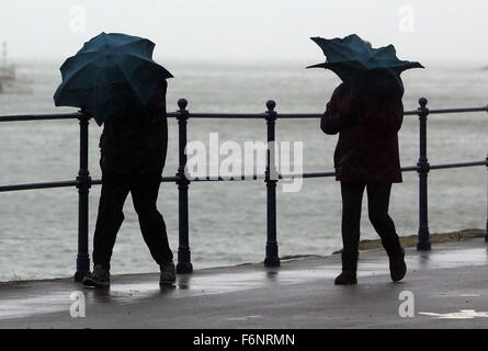 Swansea, Royaume-Uni. Le mercredi 18 novembre 2015 Photo : un couple en marche contre le vent avec leurs parapluies dans Mumbles près de Swansea, Pays de Galles au Royaume-Uni. Re : Des vents forts ont été touchant certaines parties du Royaume-Uni. Credit : D Legakis/Alamy Live News Banque D'Images