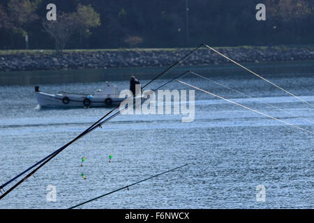 Fermer la vue des lignes de pêche et rétroéclairé avec colliers à l'alarme. Bateau de pêcheurs loin en arrière-plan. Banque D'Images